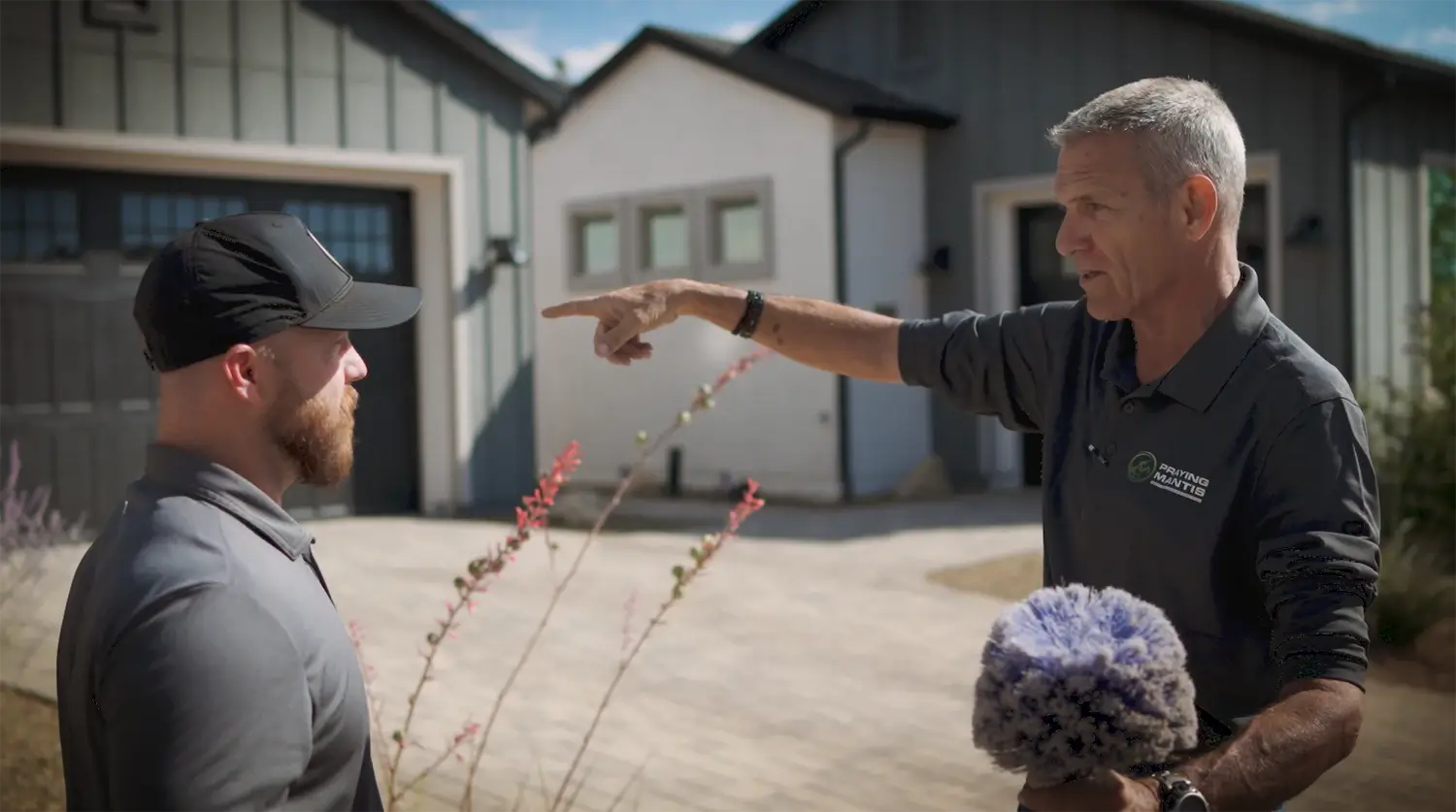 Pest control professionals discussing treatment plan outside residential home